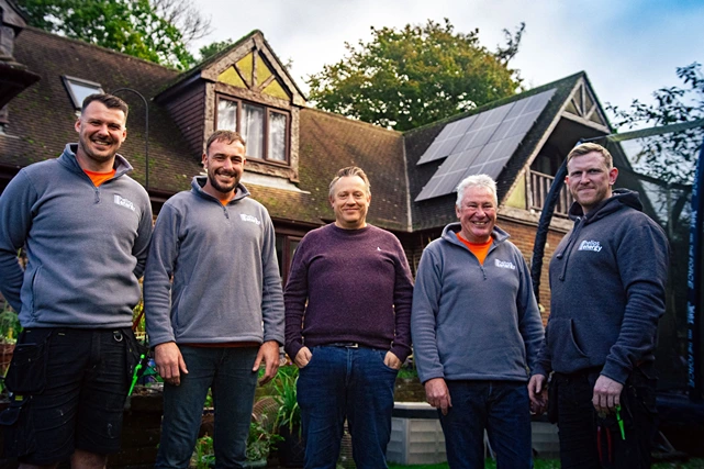 The Helios Energy team with a client after a solar panel installation.